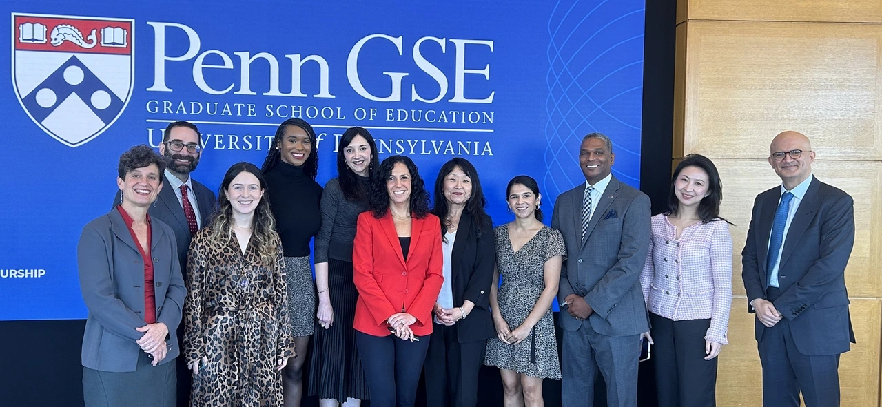 EdEnt Founding Director Jenny Zapf (far left), Penn GSE Dean Katharine Strunk (fourth from right), Associate Dean Susan Yoon (third from right), and six EdEnt program alum from five different cohorts pose in business casual attire in front of a blue Penn GSE banner.