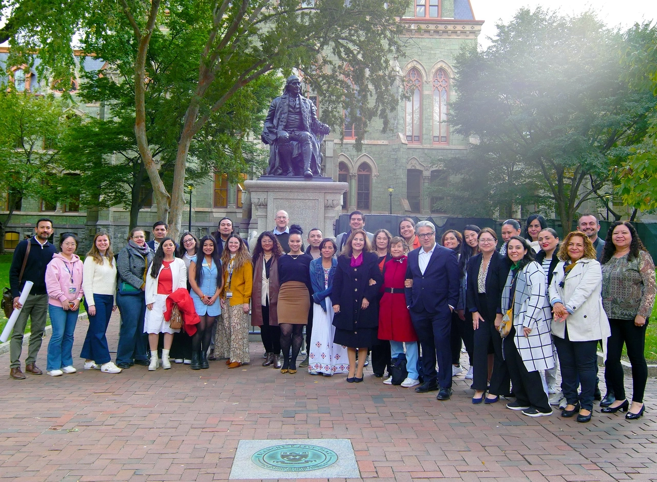 Researchers from Penn GSE and University of Guadalajara pose together in front of the Ben Franklin Statue in the center of Penn's campus during a literacy conference
