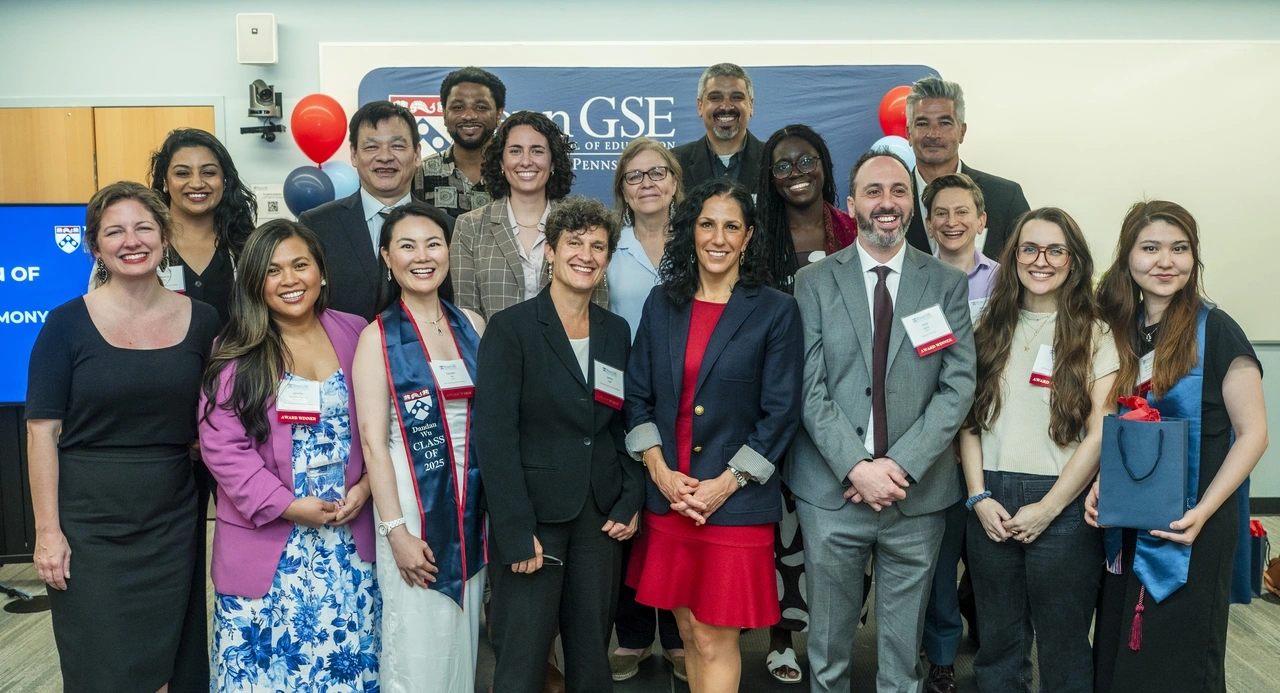 Dean Strunk poses, smiling, with 16 staff, faculty, and alumni award winners