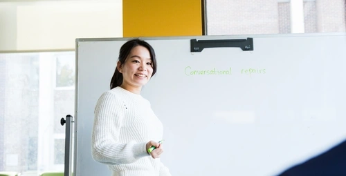 TESOL student standing in front of a whiteboard 