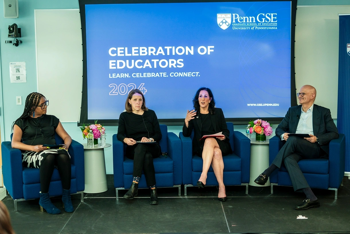 From left, Ericka Weathers; Rachel Baker; Dean Katharine Strunk; and moderator, alum, and Board of Advisors member Navin M. Valrani sit in blue chairs engaged in discussion underneath a screen that reads, “Celebration of Educators 2024: Learn. Celebrate. Connect.”