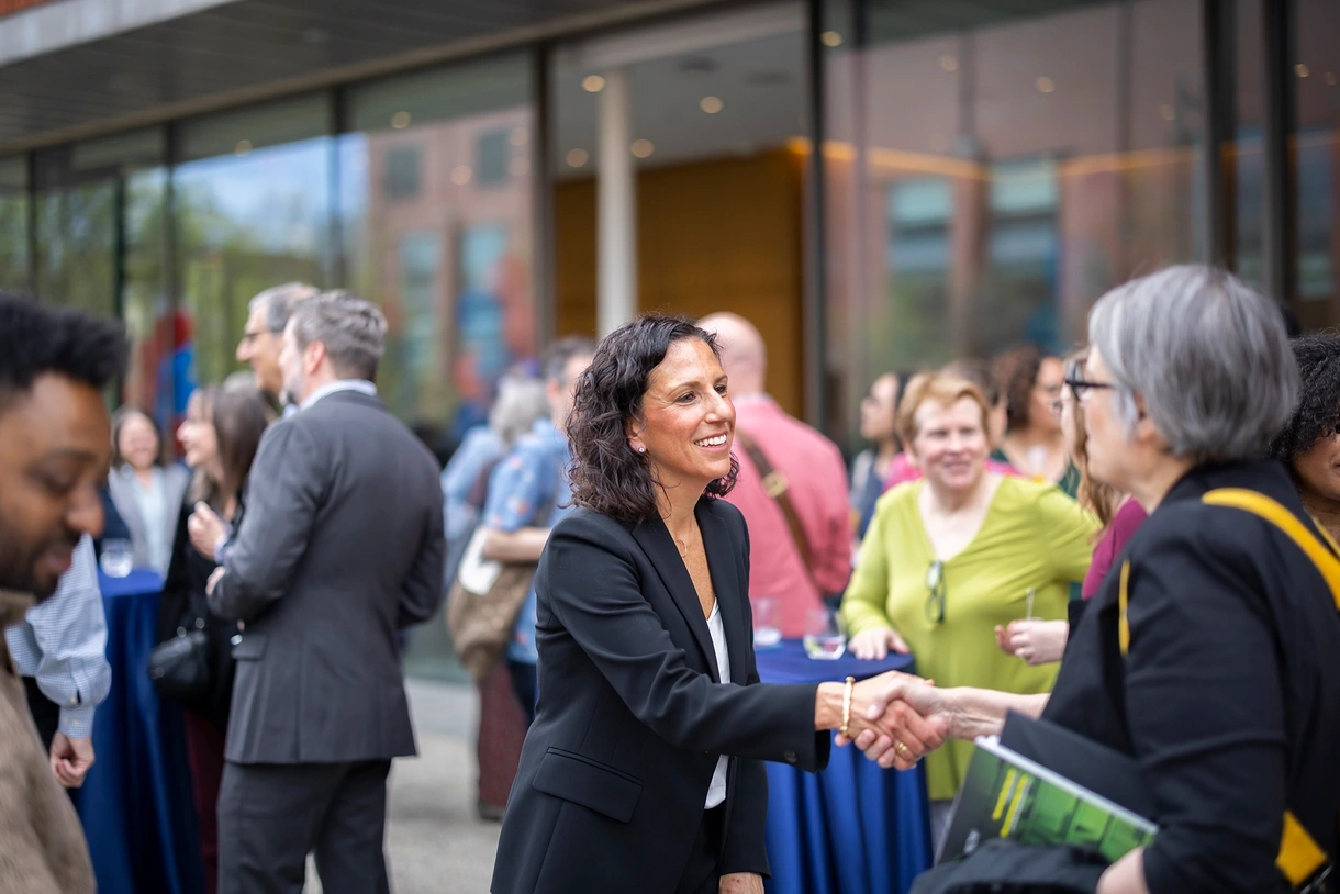 Penn GSE Dean Katharine Strunk greets attendees at an outdoor event.