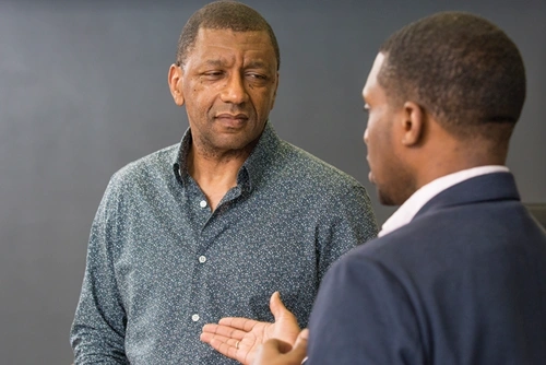 Dr. Stevenson stands in front of a chalkboard conversing with a student.