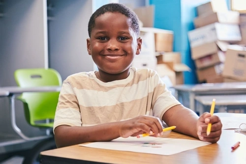 Child student smiling and holding pencils