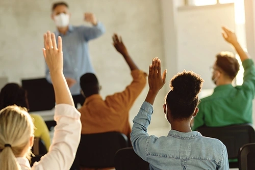 Students raising their hands in a classroom