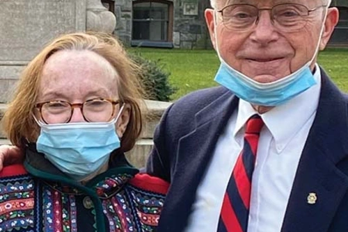Susan Cotton and Doug Cotton are seen with masks against the backdrop of College Hall at Penn. Photo by Jane Lindahl