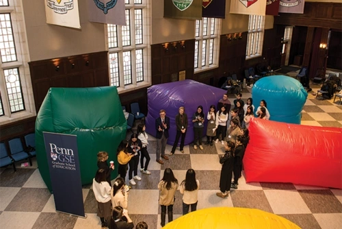 Penn GSE students standing in a circle with large plastic inflatables behind them