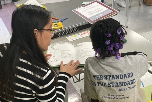 Penn Arts & Sciences undergrad Johana Muñoz tutors a Hamilton Elementary student in reading at a desk in a classroom