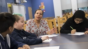 A teacher and students sit around a table, before COVID-19.