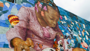 Outside mural of a little girl with a blue backdrop