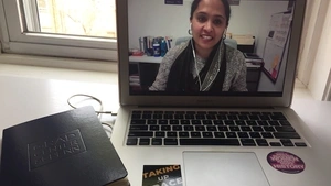 An instructor appears on a computer screen delivering an online college lesson.