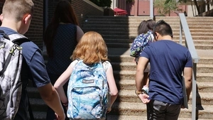 Students with backpacks walking up school steps