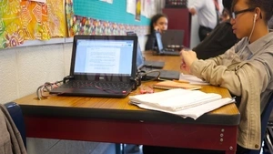 Laptop on table with students